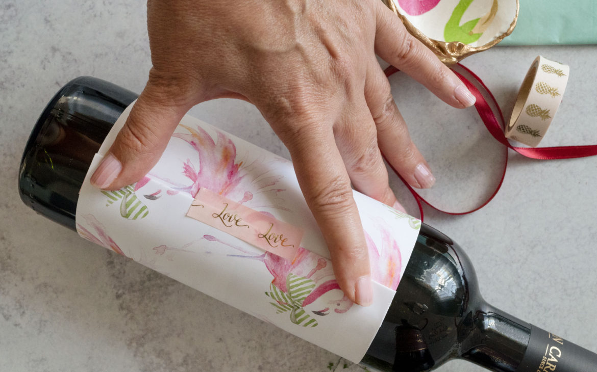 Unique wine bottle gift wrapping idea using pink flamingo wrapping paper and crafting tape. Perfect for Palm Beach and Florida Christmas hostess gifts